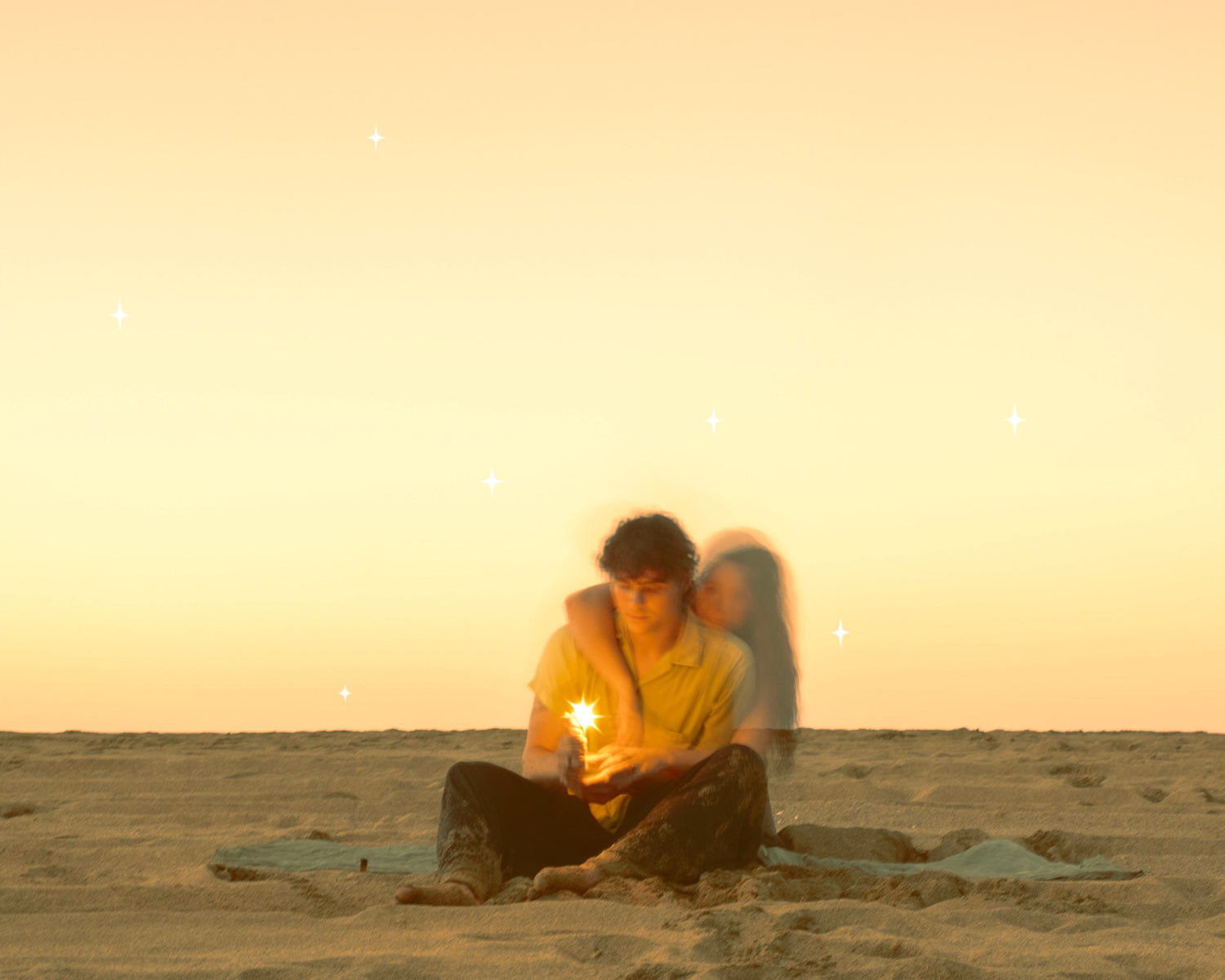 Person sitting on a beach with a lighted candle, surrounded by a starry sky.