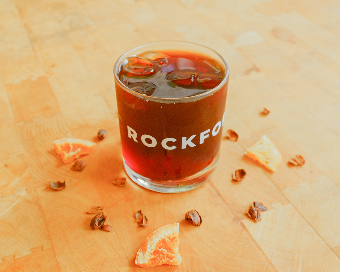 Glass of iced coffee with 'ROCKFORD' branding on a wooden surface.